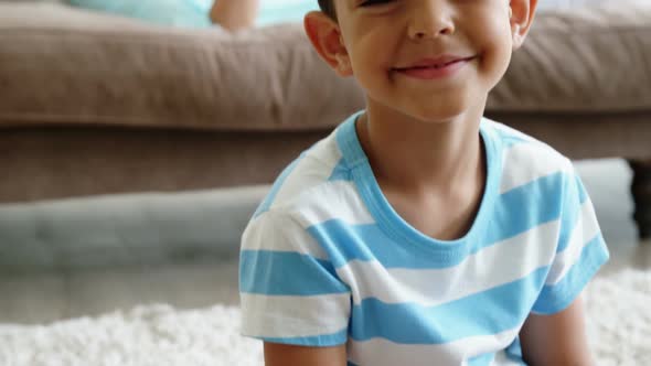 Portrait smiling boy sitting on rug in living room