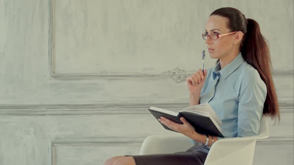 Young Beautiful Businesswoman Thinking with a Folder in Hands