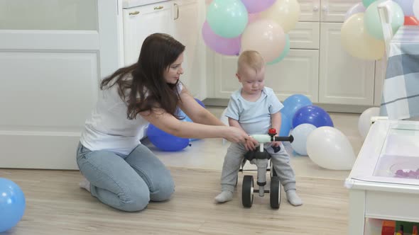 Mother and Baby Boy Play on the Floor Mother Teaches 1 Year Old Child to Ride a Balance Bike