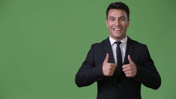 Young Handsome Hispanic Businessman Against Green Background