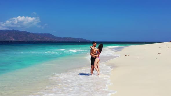 Man and woman engaged on beautiful seashore beach vacation by blue green water and bright sand backg