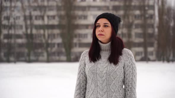 Portrait of a Beautiful Young Woman in a Gray Knitted Sweater Standing Outdoors During Winter