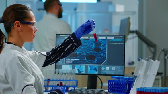 Scientist Doctor Looking at Blood Sample and Writing on Computer