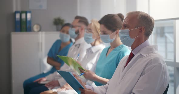 Doctors and Interns in Protective Mask Listening to Professor in Conference Room