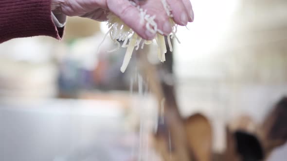 Beautiful hand throws shredded cheese onto fondue pot for preparation, slow motion