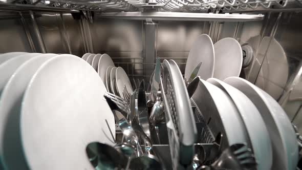 Forward Dolly Shot of Dishwasher Machine with Dishes and Silverware