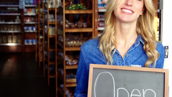 Smiling owner holding open signboard in supermarket