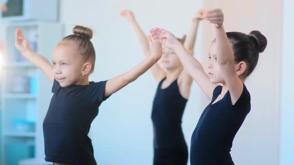 Young Girls in Tracksuits Stretch Hands Standing in Studio