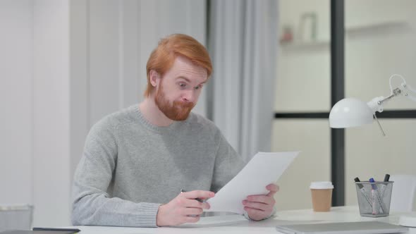 Redhead Man Reacting To Loss While Reading Papers 