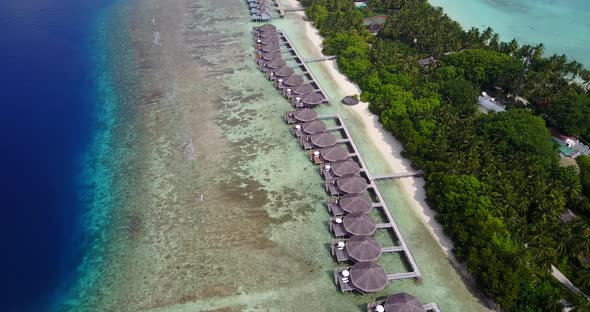 Wide drone travel shot of a paradise sunny white sand beach and blue water background in 4K