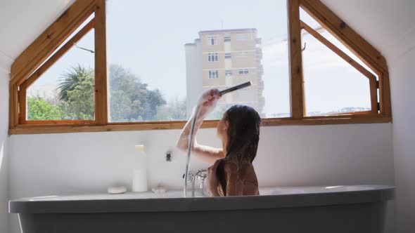 Woman showering in bathtub in bathroom