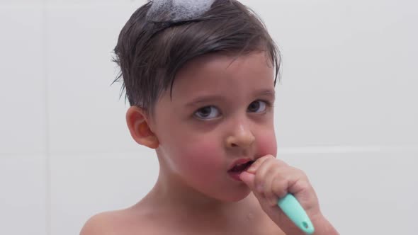 Child Brushes His Teeth While Sitting