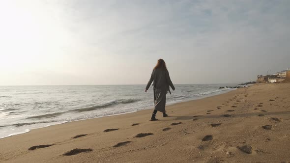 Attractive Redhead Woman in Coat Walking on the Wild Autumn Beach