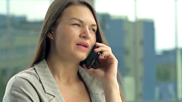 Beautiful Young Woman Talking on the Phone While Standing on a City Street