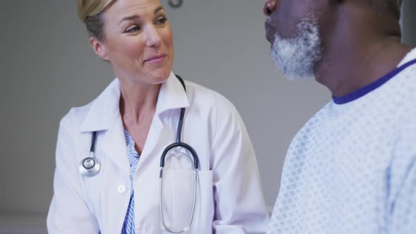 Caucasian female doctor talking to african american senior male patient at hospital