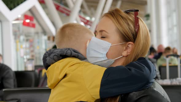 A Young Mother Hugs Her Little Son at the Airport They Have Medical Masks