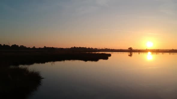 Aerial push out over water beautiful sunset lake silhouette teal orange sky