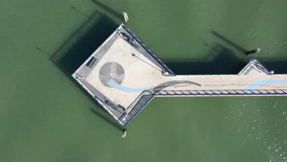 A top down shot over a pier in the green water in Red Hook Channel on a sunny morning. The camera bo