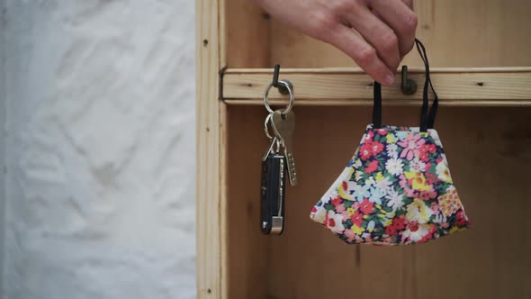 }A tight shot of hanging up keys and face mask.