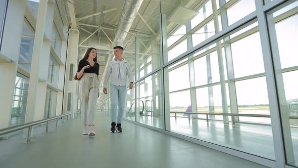A Young Woman and a Man are Talking and Walking Through the Airport