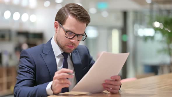 Young Businessman Reacting to Loss on Documents at Work