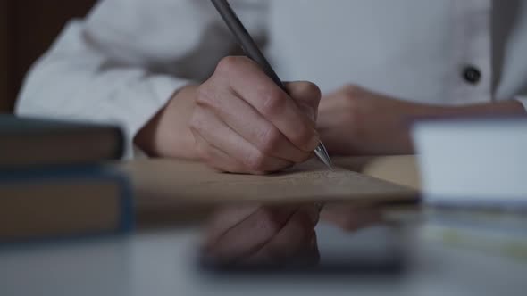 Close up of hand writing notes in personal diary of memories studies in library with book. Education