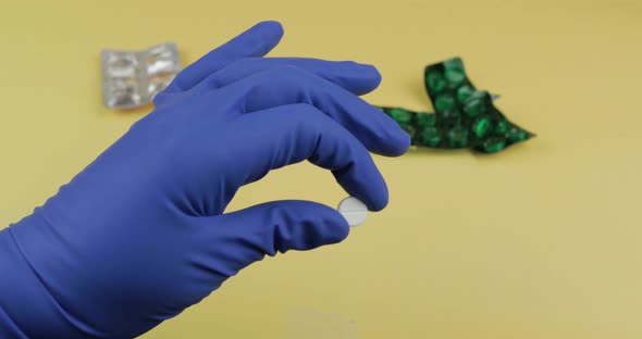 One Round White Pill in Hand Dressed in Rubber Sterile Medical Glove