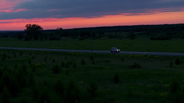 Aerial View of a Car on the Road on the Background of Sunset