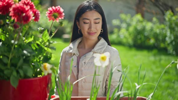 Front View Middle Shot of Young Smiling Asian Woman Looking at Camera Standing in Sunny Garden with