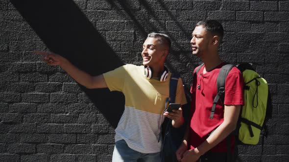 Two happy mixed race friends using smartphone in the street