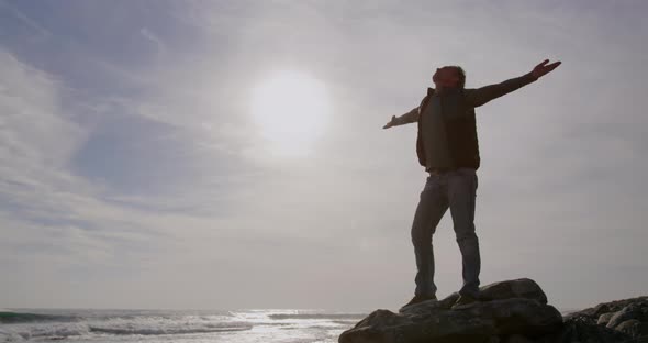 Caucasian woman enjoying free time by sea on sunny day standing with arms wide