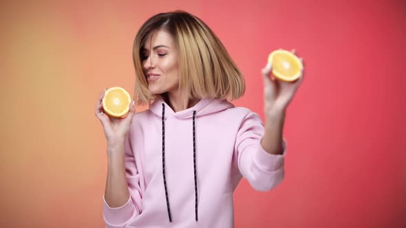 Woman in Casual Pink Clothes Holding Oranges and Dancing