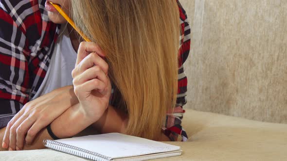 The Girl Is Writing in Her Notebook