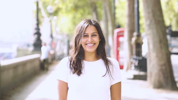 Happy young woman standing on bridge in London, UK