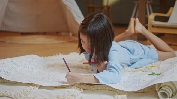 Little Asian Girl is Drawing the Picture in the Paper on the Floor Ground She Has Many Color Pencil