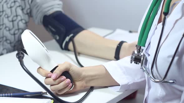 Female Doctor Measures The Blood Pressure Of Men In The Office