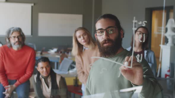 Young Man Giving Presentation on Glass Board in Office