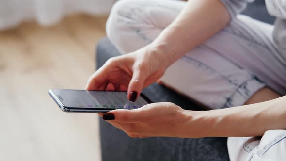 Young Female Using Smart Phones Social Media Sitting On Sofa At Home.