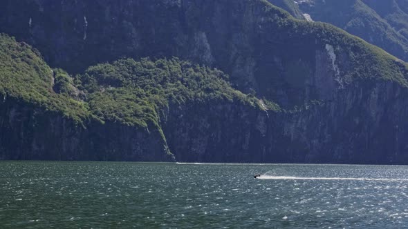 Jet Skiing At Milford Sound On A Sunny Day At Fiordland, New Zealand. - wide shot