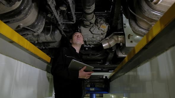 Auto mechanic makes an inspection of truck at service station.