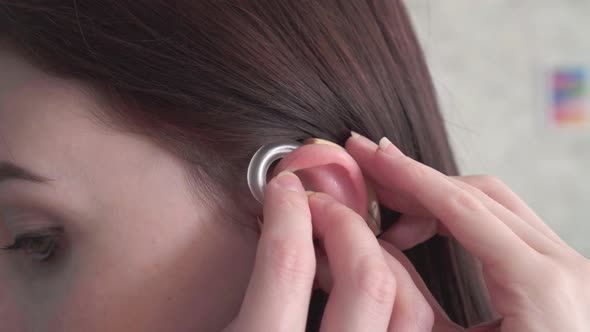 Young Woman Inserts a Hearing Aid Into Her Ear Close Up
