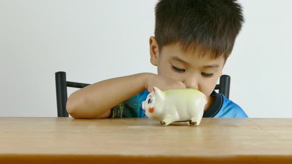 Cute Asian boy saving money in piggy bank 