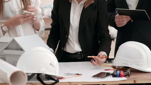 a Woman Engineer in a Circular Motion of the Hand with a Pencil Is Showing on the Drawing, and Her