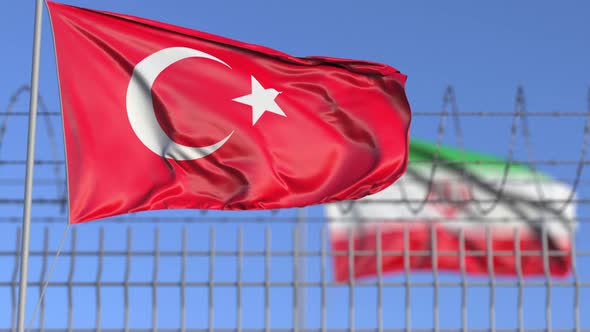 Waving Flags of Turkey and Iran Separated By Barbed Wire Fence