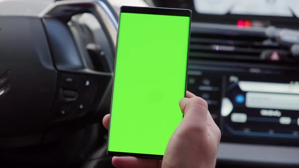 Close Up Hand of the Driver in Car Uses a Smartphone with a Green Screen Inside a Car