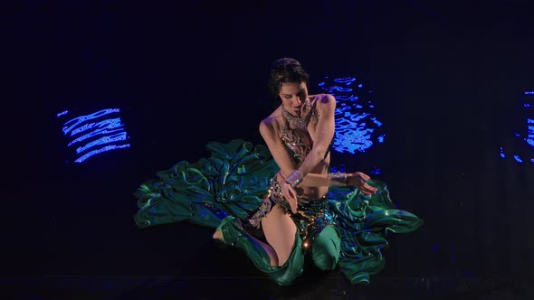 Top View of a Wet Oriental Woman Sitting on the Surface of the Water and Dancing a Belly Dance