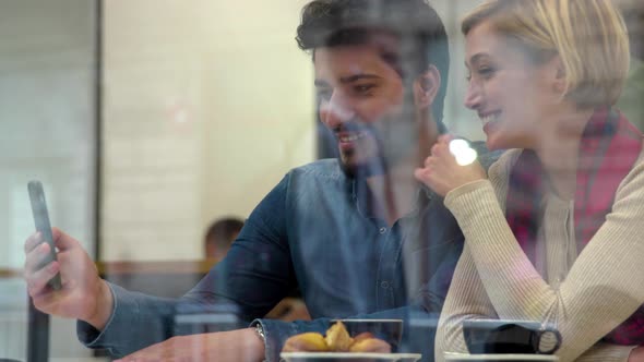 Technology. Happy people with mobile phone having fun in cafe