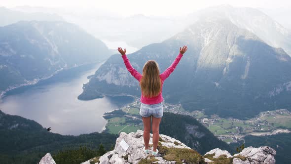 Back View of Young Woman Rise Her Hands Enjoying Amazing View of Lake in Mountains