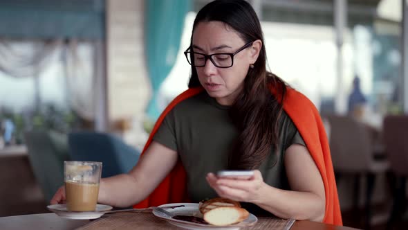 A Middleaged Businesswoman Sits in a Cafe on Her Lunch Break and Talks Via Video Link Via Phone