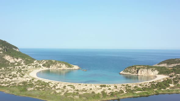 Aerial drone video of semicircular sandy beach and lagoon of Voidokilia